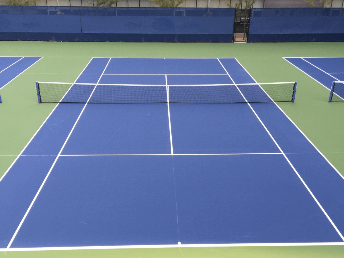 Empty outdoor blue and green tennis court with white boundary lines and a net in the center.