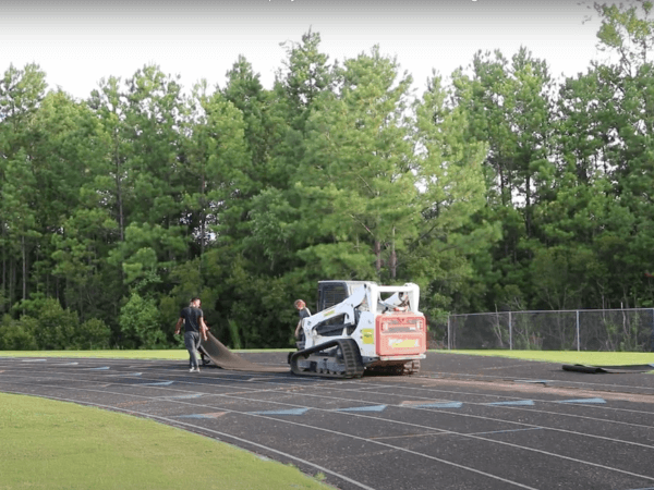 A man is standing next to a bulldozer on a track.
