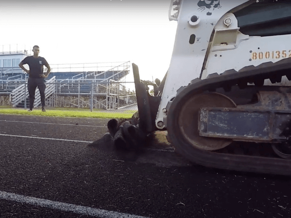 A man is standing next to a bulldozer on a track.