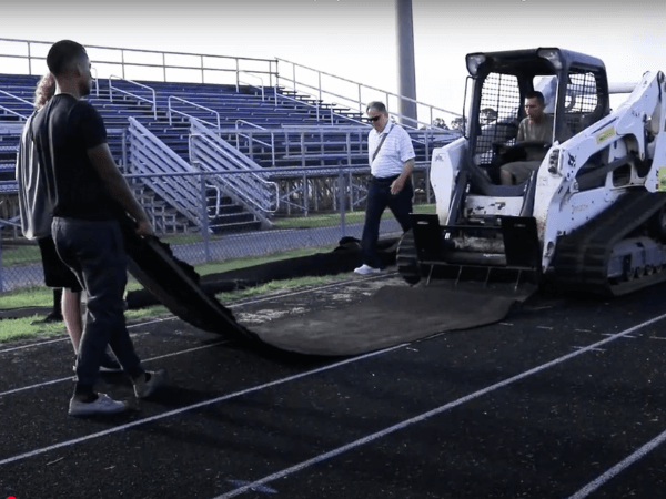 A man is standing next to a bulldozer on a track.
