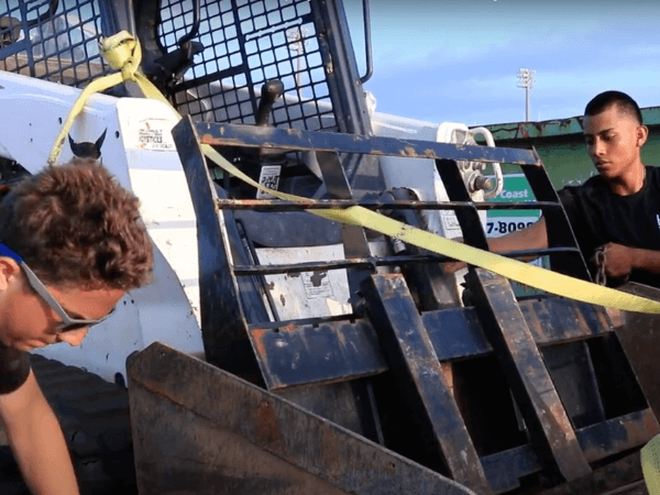 Two men are working on a bulldozer.