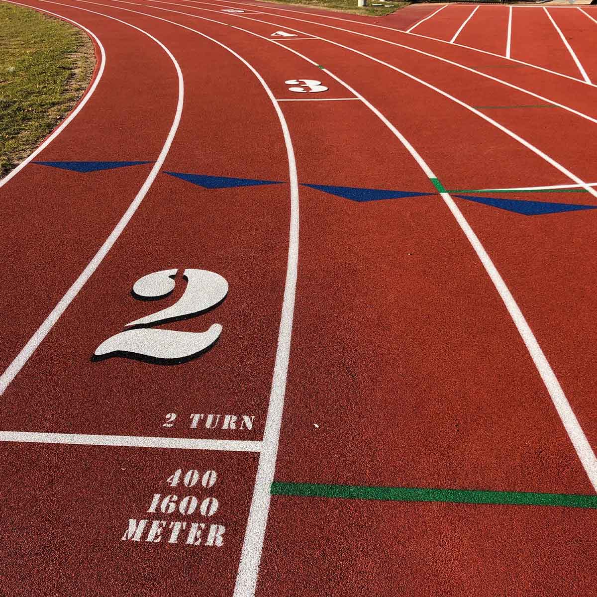 A red running track with white lane markings, including lane numbers and distance indicators for 400 and 1600 meters, and green and blue guide lines.