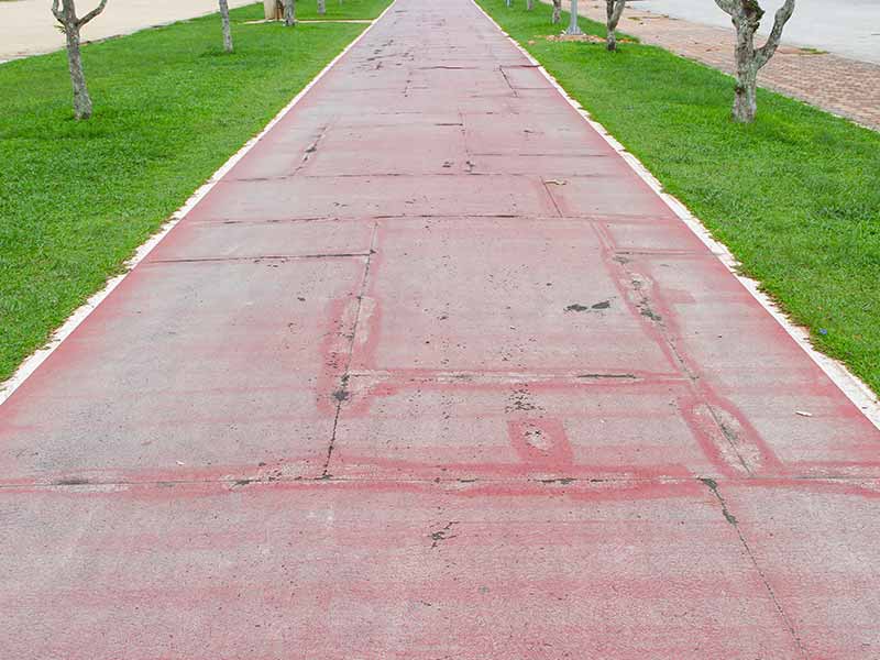 A red road with a tree in the middle.