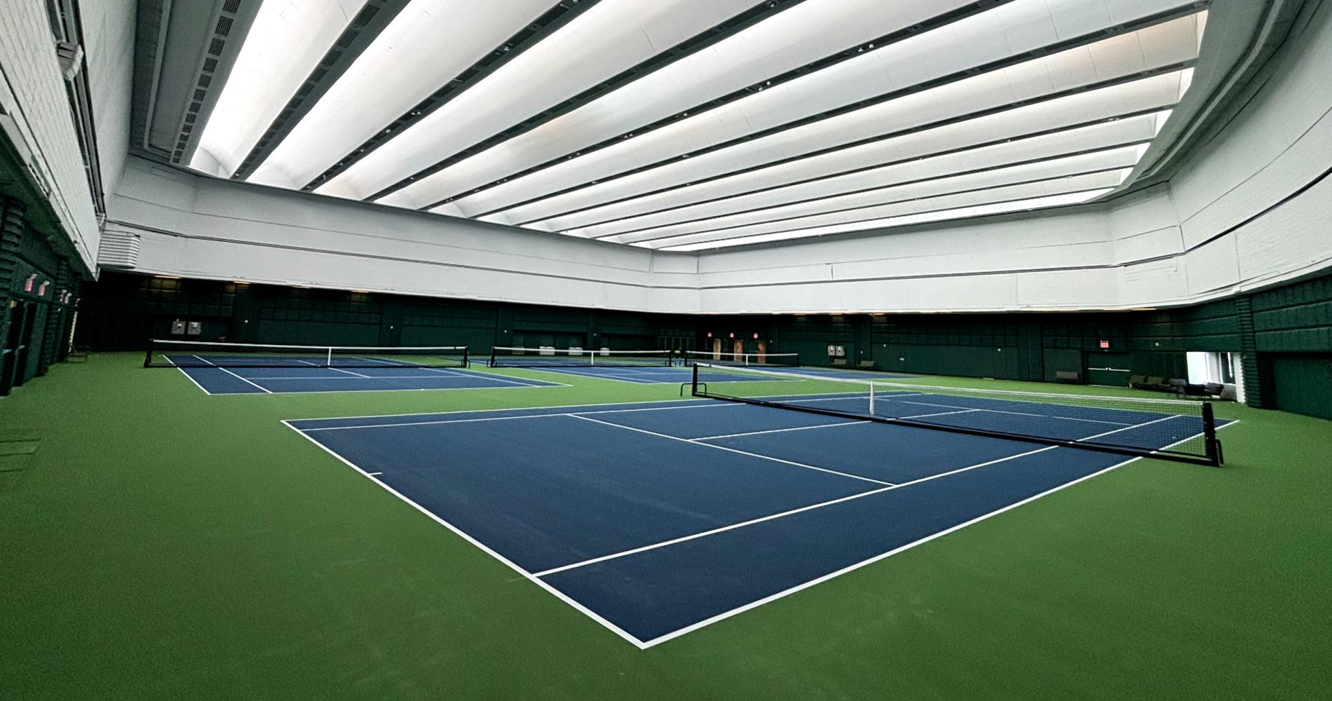 A tennis court with a ceiling that is lit up.